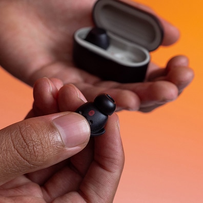 Close up of a pair of hands holding an LG xboom Buds and the carrying case.
